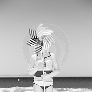 Child on beach holding windmill toy in front of face