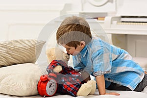 Child in bedroom kiss toy in nose. Good night concept. Boy with happy face puts favourite toy on bed, wishing sweet