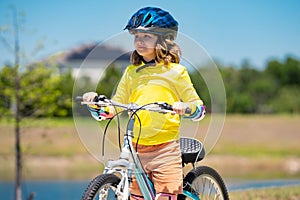 Child on bicycle. Boy in a helmet riding bike. Little cute caucasian boy in safety helmet riding bike in city park