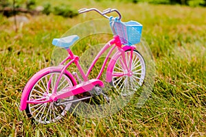 Child bicycle on the lawn.Minimal concept. Plastic bicycle toy over grass background. Pink bike. Travel concept of