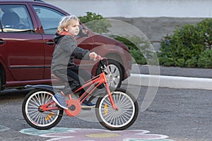 Child on Bicycle on paved road near car. Safety of children