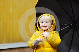 Child with big black umbrella in the rain