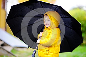 Child with big black umbrella in the rain