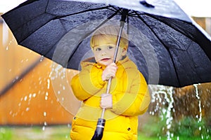 Child with big black umbrella in the rain