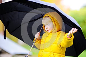 Child with big black umbrella in the rain