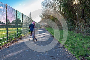 Child on the bike looking back and smiling on the path by the fence