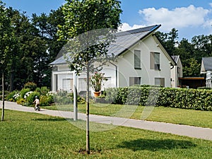 Child Biking Past Modern House with Solar Panels