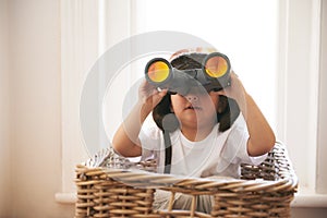 Child, binocular and hat for game of creativity, adventure or expedition in toy basket at home. Fun, curious and