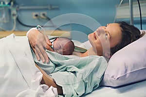 Child birth in maternity hospital. Mother and newborn. Young mom hugging her newborn baby after delivery. Woman giving birth