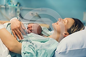 Child birth in maternity hospital. Mother and newborn. Young mom hugging her newborn baby after delivery. Woman giving birth