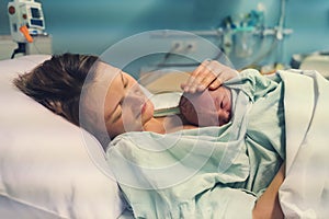 Child birth in maternity hospital. Mother and newborn. Young mom hugging her newborn baby after delivery. Woman giving birth