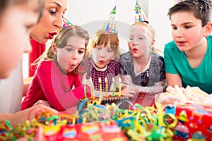 Child on birthday party blowing candles on cake