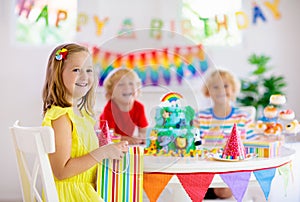 Child birthday party. Kids blow candle on cake