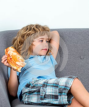 Child biting off big slice fresh made pizza. Little boy eating pizza. Cute little boy eats pizzas. Teen boy holding