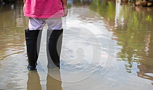 A child with black boots walks on a flooded road