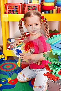 Child with block and construction in play room.