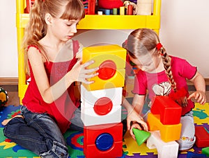 Child with block and construction in play room.