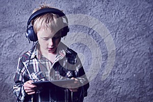 Child blond Boy listening to music or watching movie with headphones and using digital table