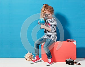 Child blonde girl with pink vintage suitcase study the globe. Travel and adventure concept
