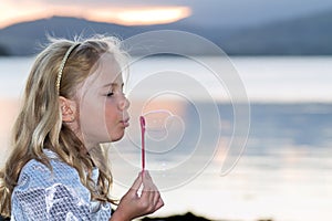 Child blowing bubbles by the sea