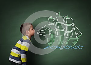 Child blowing a chalk sailboat photo