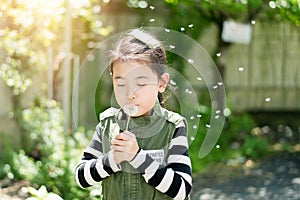 Child blowing a dandelion in a park.