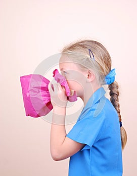 Child blowing pink paper bag