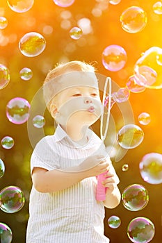 Child blowing a soap bubbles. Boy playing. Kid blowing bubbles o