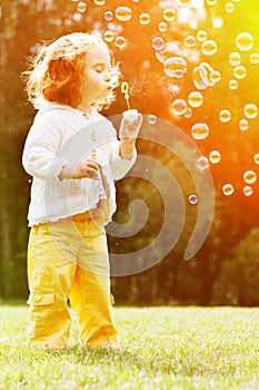 Child blowing a soap bubbles. Kid blowing bubbles on nature. Bab
