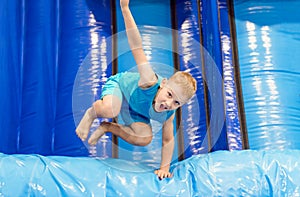 Child on blue playground trampoline. Kids jump in inflatable bounce castle on kindergarten birthday party. Activity and play cente