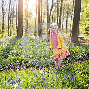 Child with bluebell flowers in spring forest