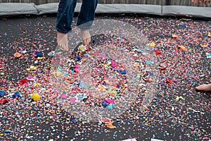 Child bouncing on trampoline covered in egg shells and confetti