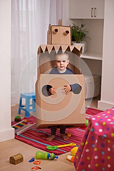 Child, box and play for robot and imagination in bedroom for fun and recreation in home on weekend. Young kid, toddler