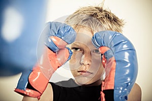 Child with boxing gloves focusing on punching pad