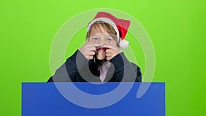 Child boy appeared from behind a blue poster bares his teeth shakes his head and curves of faces and hidden again. Green