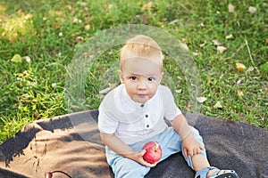 Child boy with apples in park on picnic. Autumn family walk in forest. Happy baby boy in autumn park. Family and mother`s day.