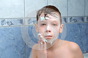 Child boy is applying alginate mask lying in bathroom with foam at home.