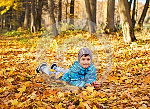 Child boy in autumn park with foliage.