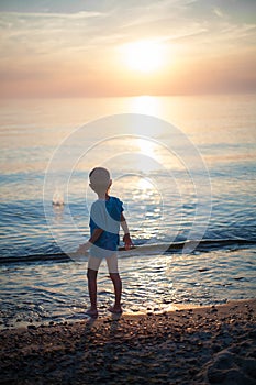 Child boy on beach sunset backlight