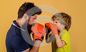 Child boy in boxing gloves training with coach. Punching knockout. Father and son in sportswear.
