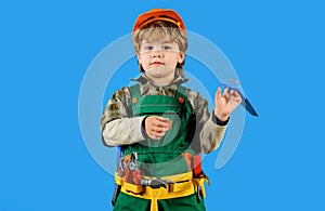 Child boy in builder uniform with tool belt. Tools for building. Little kid in overalls and safety helmet with builders