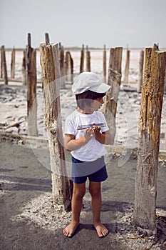 Child boy in a cap t shirt and shorts holds a phone in his hand