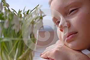 Child boy close up looking at snowdrops