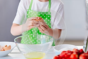 Child boy cracking egg and separating the yolk