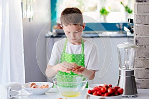 Child boy cracking egg and separating the yolk