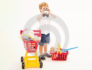 Child boy with credit card. Shopping, discount and sale. Happy little kid with shopping cart and basket. photo