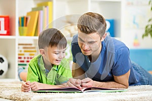 Child boy and dad read a book on floor at home