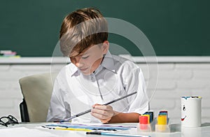 Child boy drawing with coloring pens, painting with early development paints. Childhood learning, kids artistics skills.