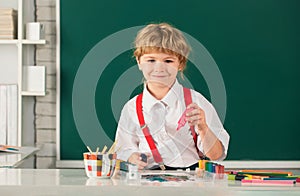 Child boy drawing with coloring pens, painting with early development paints. Portrait school kid boy doing art homework