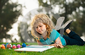 Child boy drawing in summer park, painting art. Little artist painter draw pictures outdoor. Children hobby, happy